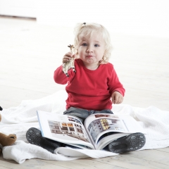 Lille pige med billedbogen holder en legetøjsgiraf